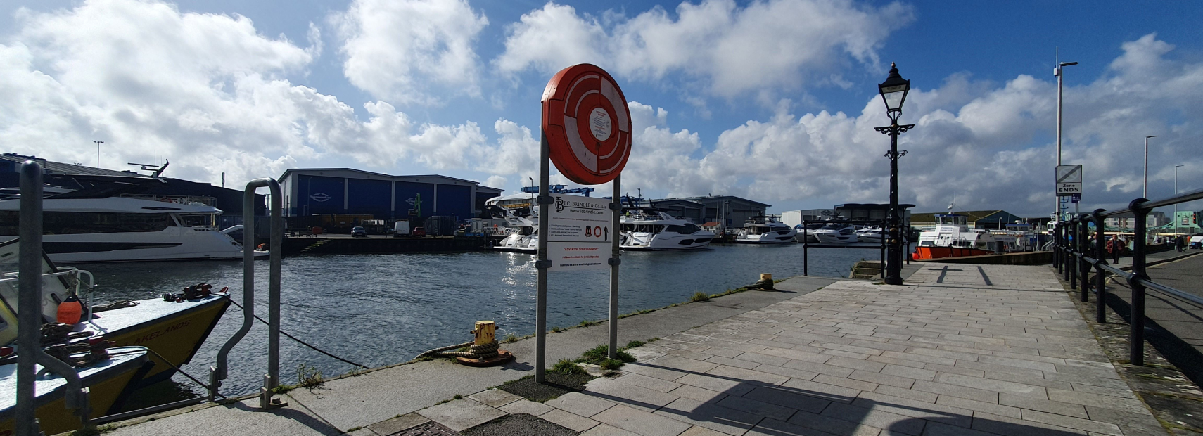 Hard Surface Lifebuoy Housing with Ad Space Signage, situated on Poole Quay, providing safety equipment and advertising opportunities in a busy waterfront setting.