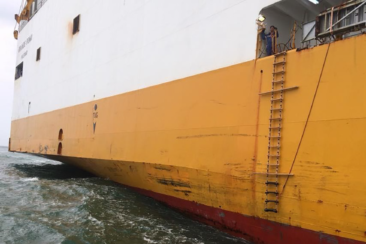  The image depicts a vessel's side with a pilot ladder deployed downwards. The spreaders of the ladder are visible.