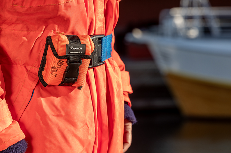 Zoom-in shot of the Tron SA20 Locator Beacon, attached to the buckle of a worker's orange overalls.