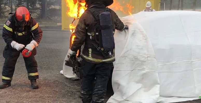 Firefighter deploying an Aerosol Potassium Salt Unit, while the EV fire blanket contains and controls the fire, preventing further spread.